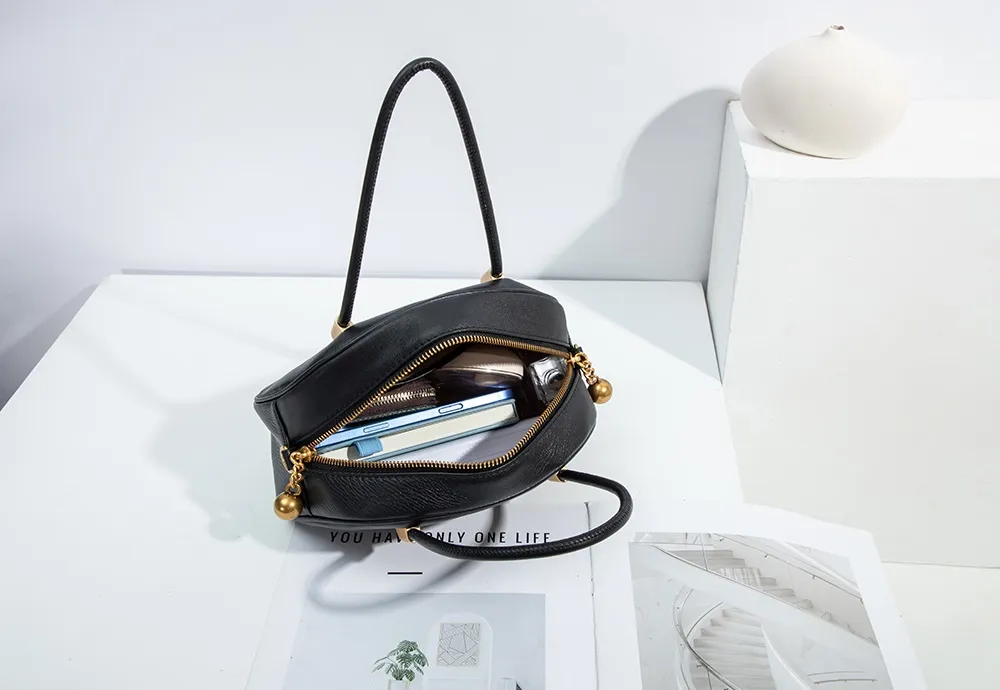 BALIYA's shell bag, with its seemingly small and round shape, features a large golden zipper for smooth and unimpeded access to items.